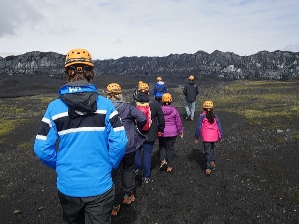 Tourists are heading for the Katla ice walk, they have helmets on.