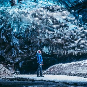 A tourist is admiring icicles on the ceiling of ice cave.