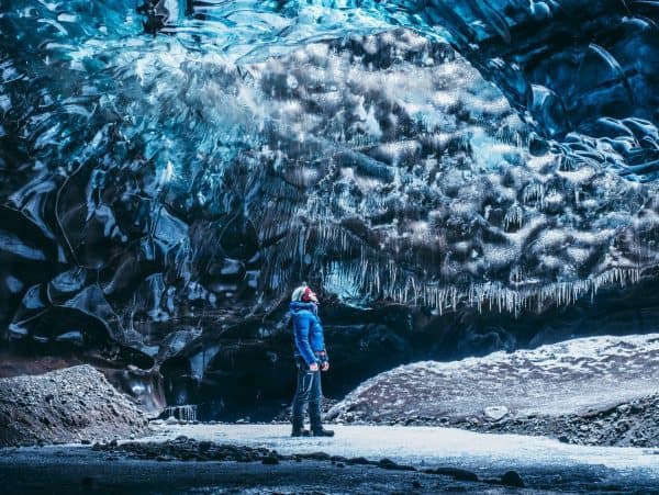 A tourist is admiring icicles on the ceiling of ice cave.